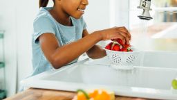 Black girl washing strawberries in kitchen