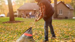 man raking leaves in his backyard