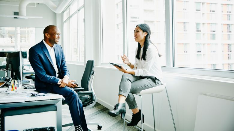 Smiling businessman and businesswoman discussing project at office workstation