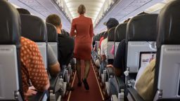 Female cabin crew walks away down aircraft cabin isle