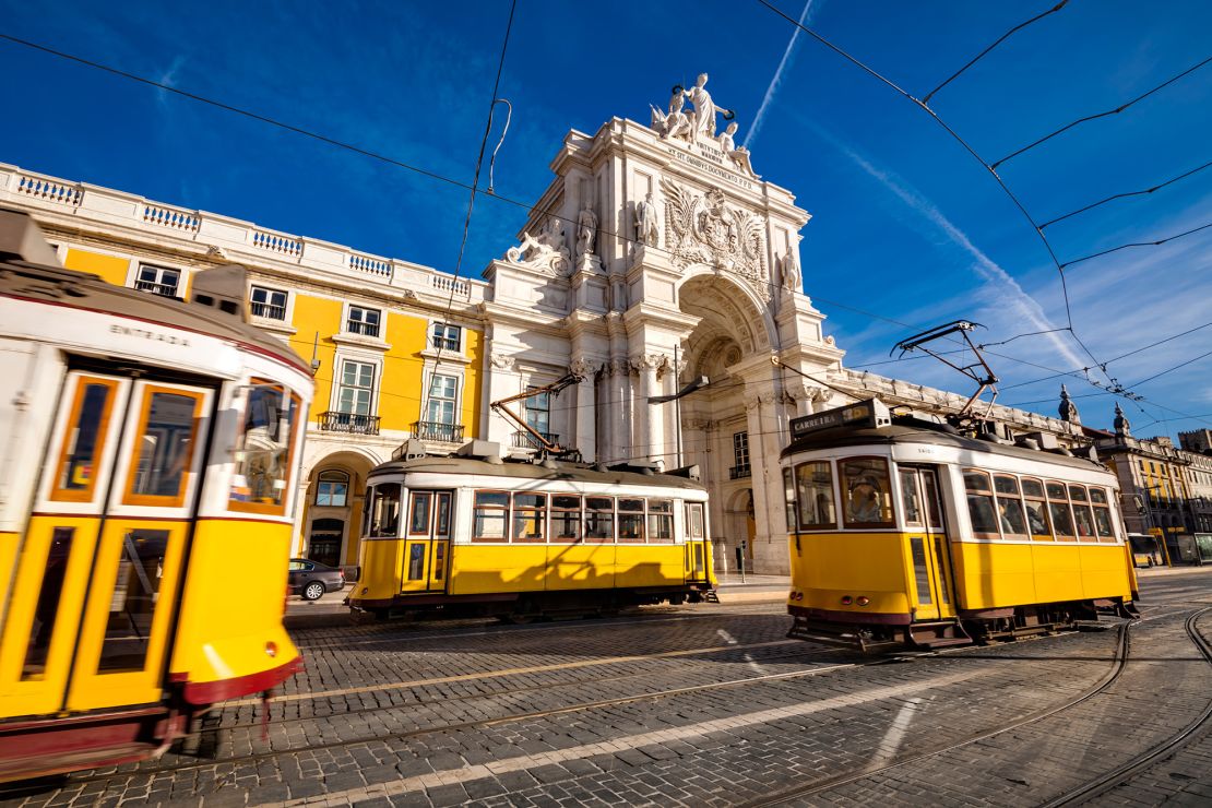 Lisbon's traditional trams pass in front of the Rua Augusta Arch.