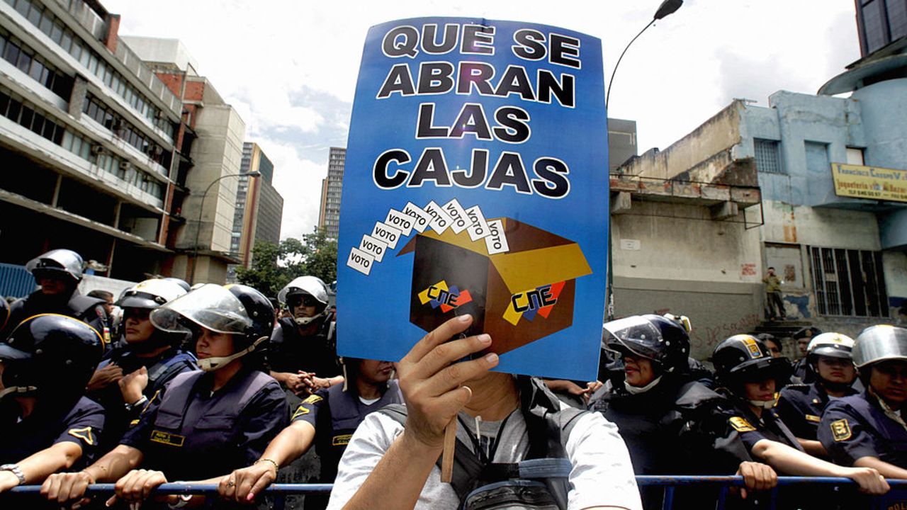 Caracas, VENEZUELA:  Un opositor al presidente de Venezuela Hugo Chavez porta un cartel alusivo al Consejo Nacional Electoral (CNE) en una manifestacion en el centro de Caracas el 15 de julio de 2006. Varios miles de opositores marcharon este sabado por las calles centricas de la capital de Venezuela para exigir condiciones de equidad para participar en las elecciones en las que el presidente Chavez buscara su reeleccion el 3 de diciembre.   AFP PHOTO/Juan BARRETO  (Photo credit should read JUAN BARRETO/AFP via Getty Images)