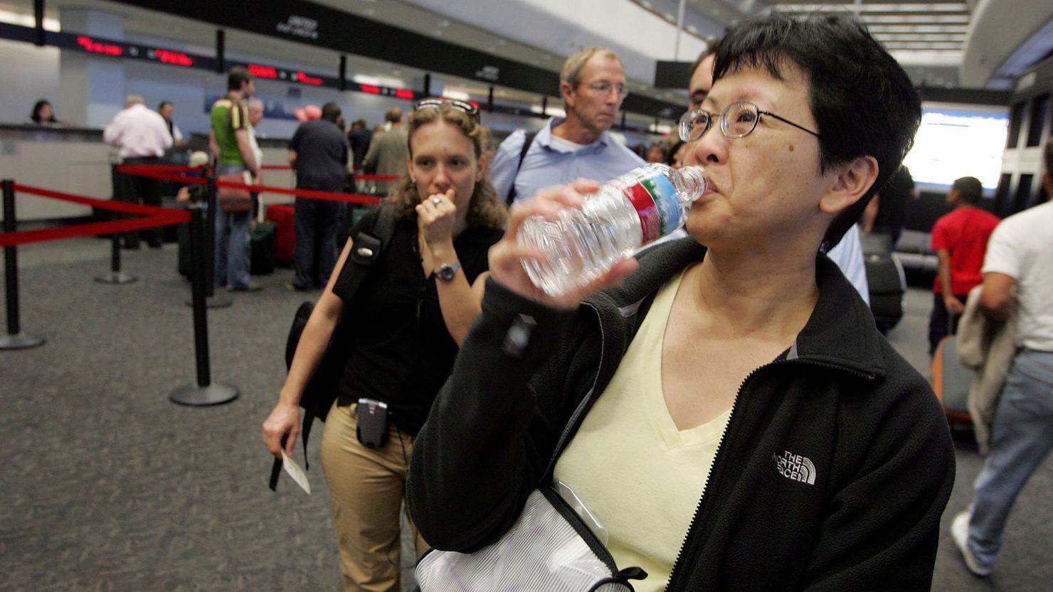 A passenger takes a sip of water before throwing away the bottle at a security checkpoint at San Francisco International Airport.