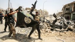  of the Iraqi Counter-Terrorism Service (CTS) cheer as they carry upside-down a black flag of the Islamic State (IS) group, with the destroyed Al-Nuri mosque seen in the background, in the Old City of Mosul on July 2, 2017, during the offensive to retake the city from IS fighters. Explosions on the evening of June 21, 2017 levelled the mosque where Abu Bakr al-Baghdadi gave his first sermon as leader of the Islamic State group, along with its ancient minaret. (Photo by AHMAD AL-RUBAYE / AFP) (Photo by AHMAD AL-RUBAYE/AFP via Getty Images)