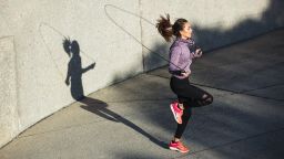 Fitness woman skipping with a jump rope outdoors. Female doing fitness training in morning.