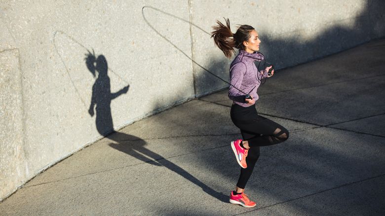 Fitness woman skipping with a jump rope outdoors. Female doing fitness training in morning.