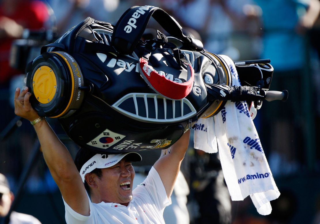 Yang triumphantly lofts his golf bag above his head.