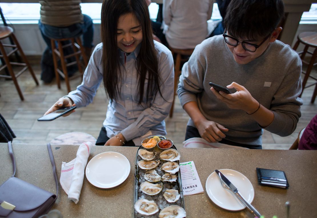 Diners take pictures of their assortment of oysters while dining at Eventide.