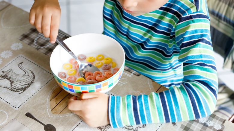 little school kid boy eating cereals with milk and berries, fresh strawberry for breakfast or lunch. Healthy eating for children, schoolkids. At school canteen or at home. Selective focus