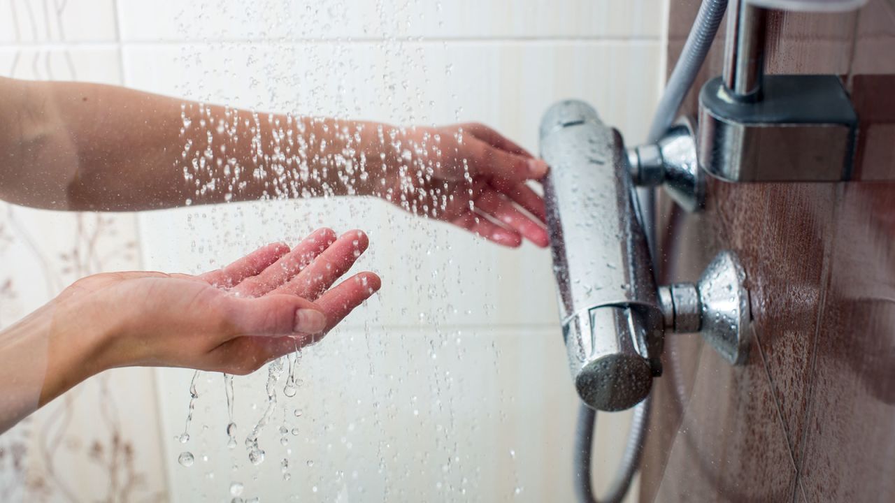 Hands of a young woman taking a hot shower at home