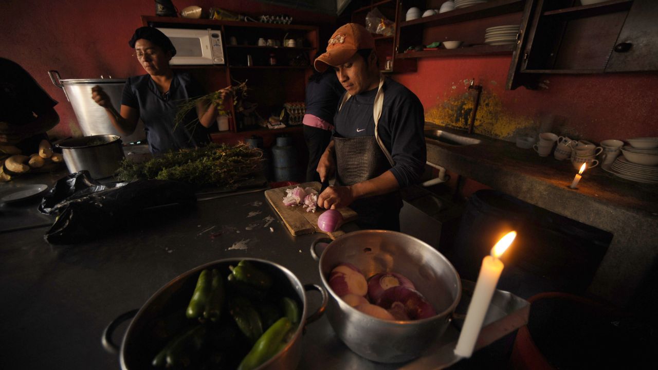 Cooks work by candlelight at a small restaurant in northern Quito the night of November 12, 2009 during a blackout as part of the government's plan to save energy. AFP PHOTO / RODRIGO BUENDIA (Photo credit should read RODRIGO BUENDIA/AFP via Getty Images)