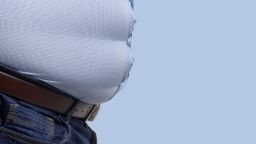 Overweight man wearing blue shirt, side view.