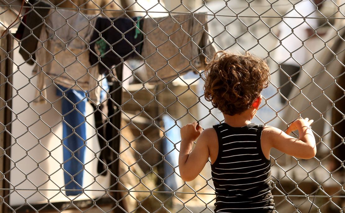 A refugee child looks through a fence at the Moria refugee camp on May 20, 2018 in Mytilene, Greece.