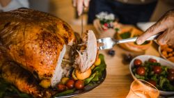 Close up of unrecognizable person carving white meat during dinner at dining table.