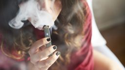 A person smokes a Juul Labs Inc. e-cigarette in this arranged photograph.