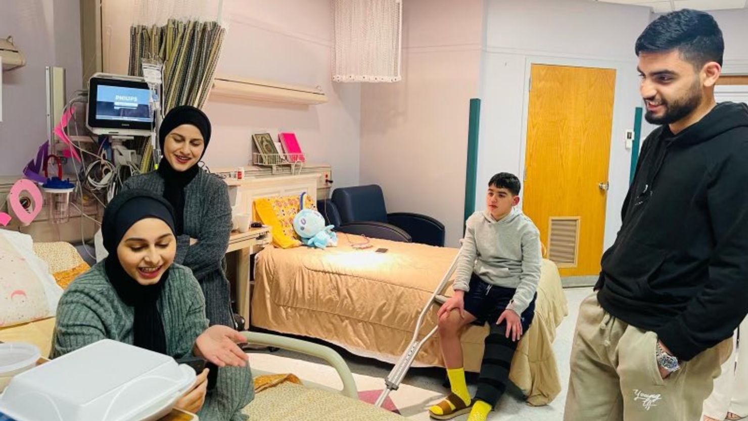 Thirteen-year-old Ayham Musalm, center, is receiving treatment for a fractured leg and glass shrapnel lodged in his knee. He was injured when debris from a strike on a neighbors’ house came straight into his home.