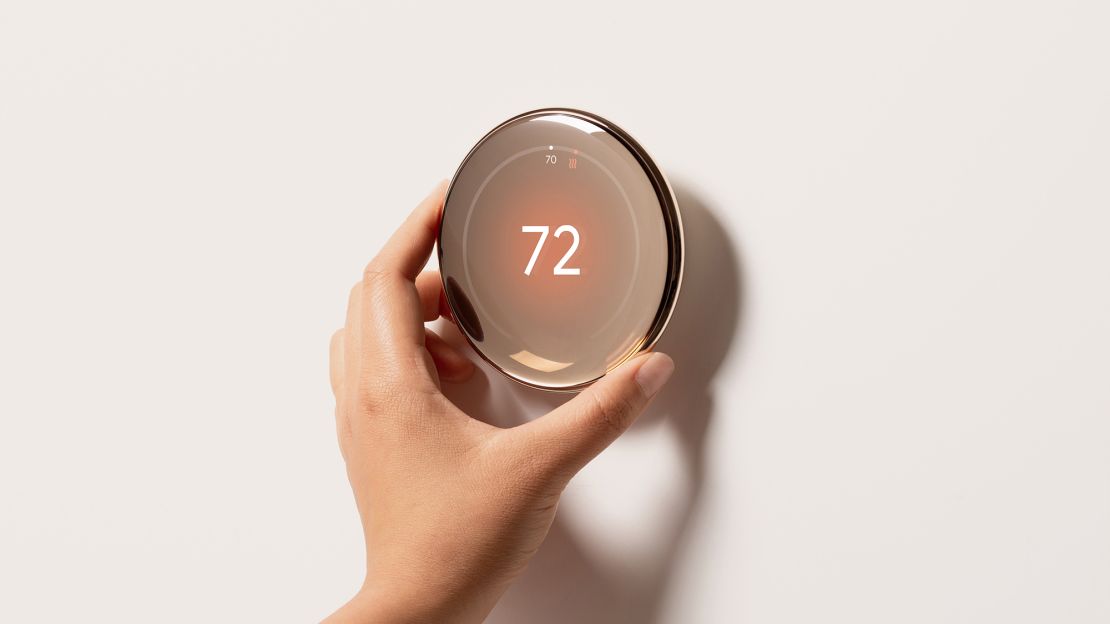 A hand adjusts the gold nest learning thermostat