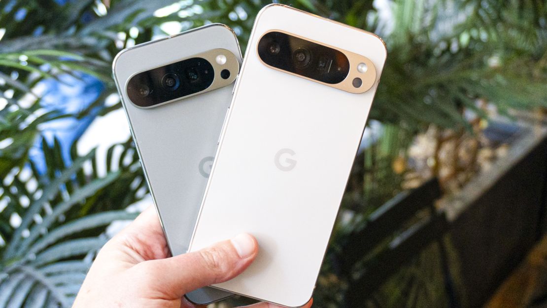 Hand holding both the Google Pixel 9 Pro and the Google Pixel 9 Pro XL.