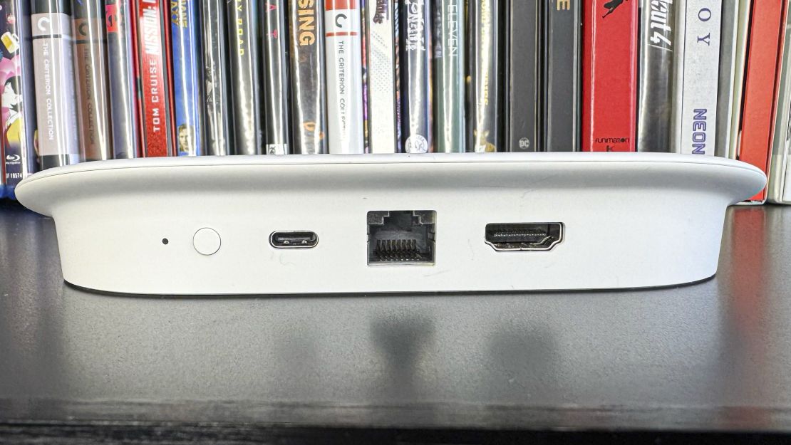 The Google TV Streamer's (L to R) remote button, and USB-C, Ethernet and HDMI ports are visible on its back — with DVDs in the background