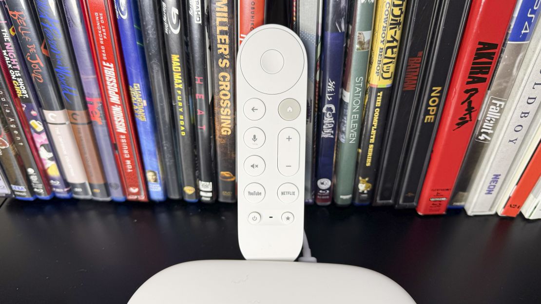 The Google TV Streamer remote sits between the box and a lot of DVDs