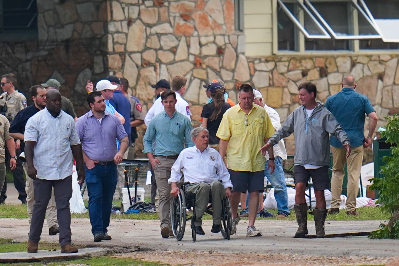 El gobernador de Texas, Greg Abbott, en el centro, recorre Camp Mystic el sábado.