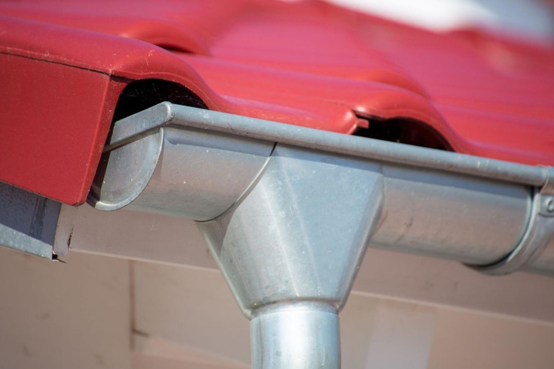 Metal gutter installed on a home with a red roof.