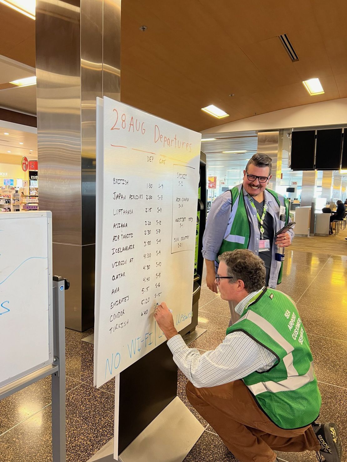 Seattle-Tacoma International Airport employees write flight information on a whiteboard during a computer system outage.