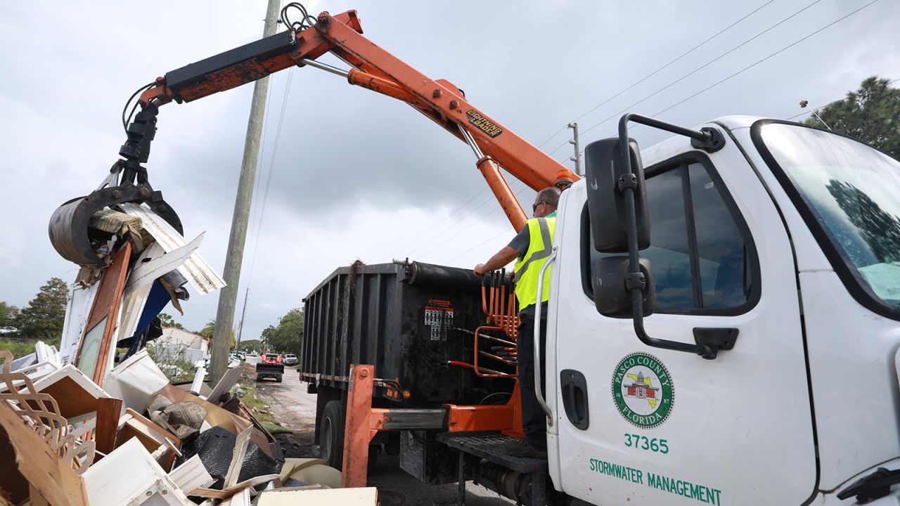 Workers remove debris along a road in Pasco County, Florida.