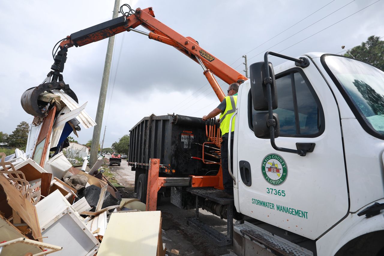 Workers remove debris along a road in Pasco County, Florida.