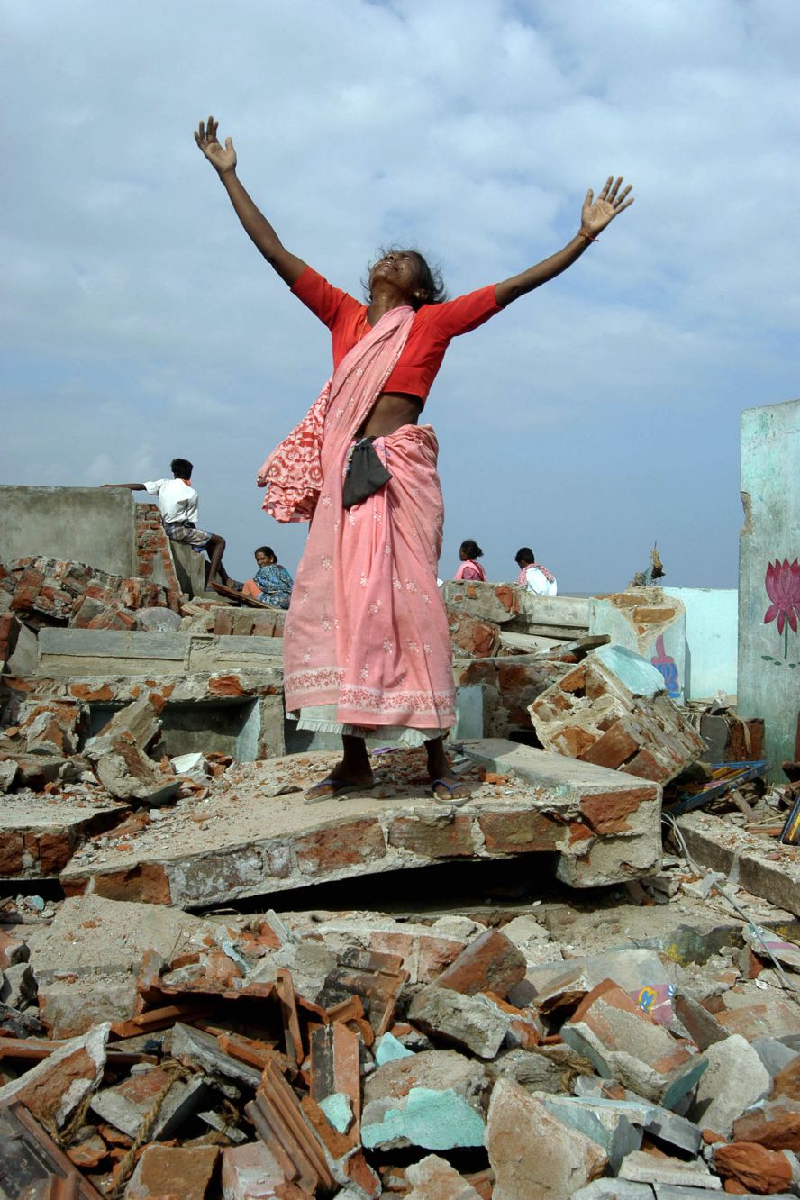 A woman mourns the loss of her family as she stands on the rubble of her home in Nagapattinam, India.