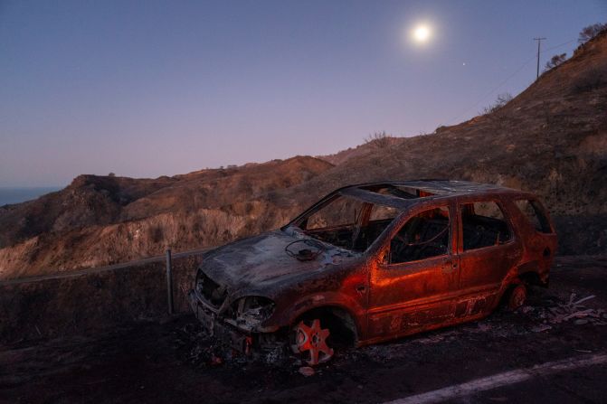 The sun rises behind a burned car in the Santa Monica Mountains.