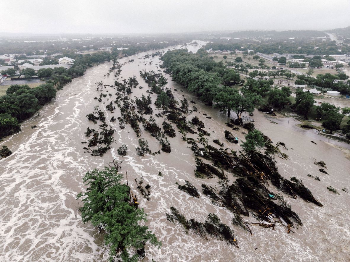 A flooded Guadalupe River leaves fallen trees and debris in its wake in Kerrville on Friday.