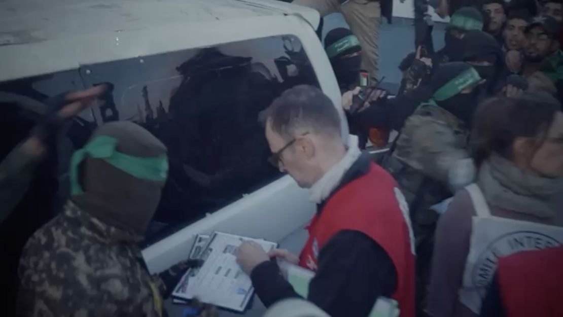 The Red Cross staff member signs a Hamas document as they take custody of three Israeli women formerly held hostage.