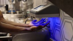 An employee at Just Salad scans their hands for contamination using PathSpot's scanner.