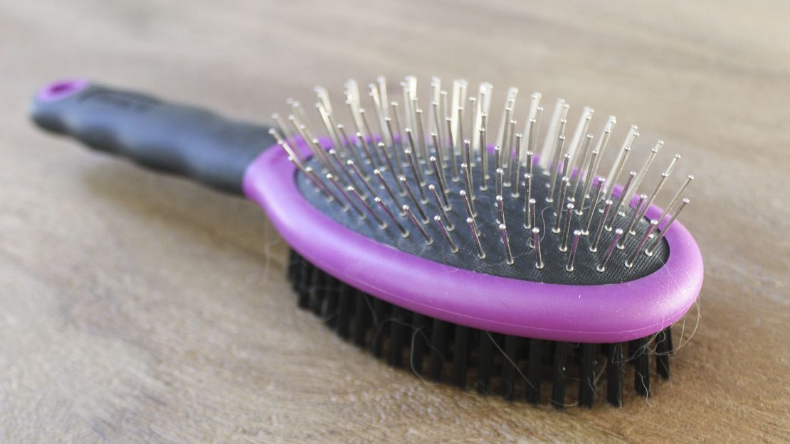 A dog-grooming brush on a wooden surface.