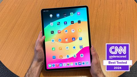 The iPad Air held in hands above a table, open to the icons on the home screen