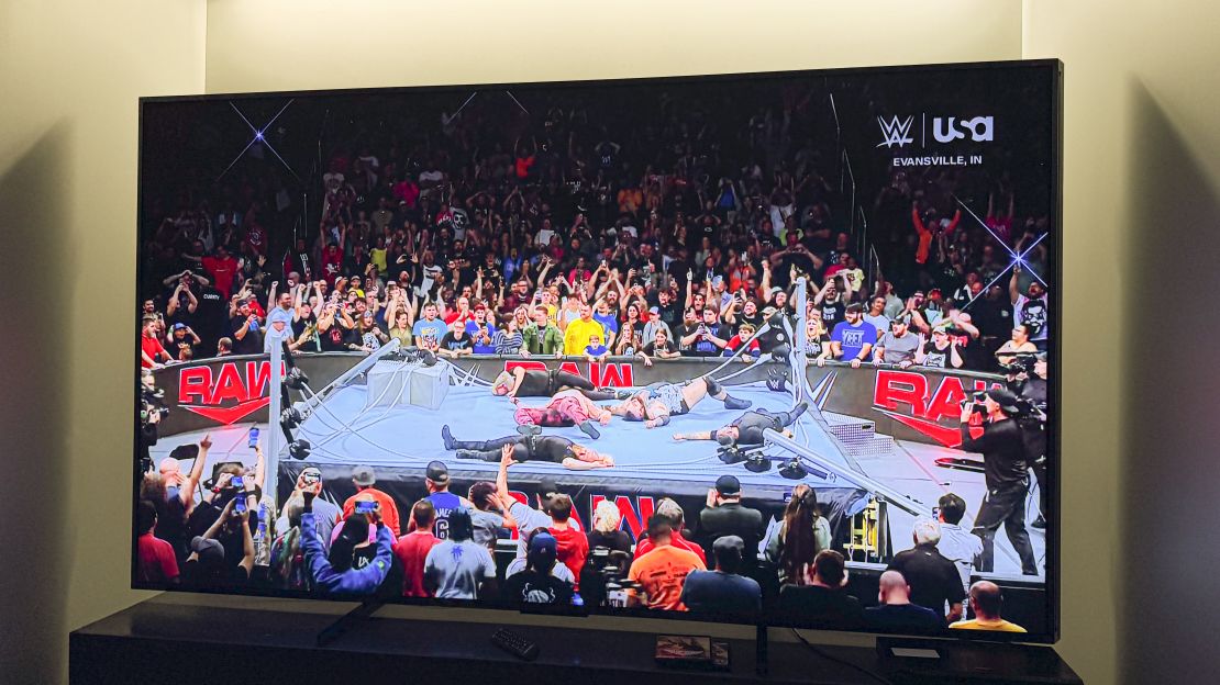 A WWE wrestling ring is collapsed and littered with bodies on the hisense 110 ux champion edition TV