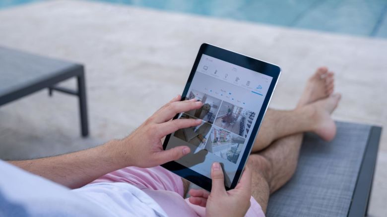 Man checking his home security cameras as he sits by the pool.