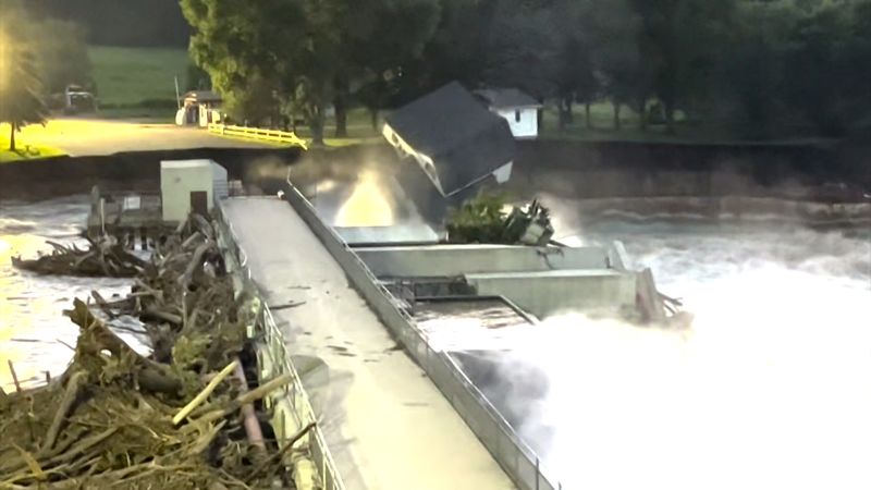 shows moment house collapses into river near failing dam