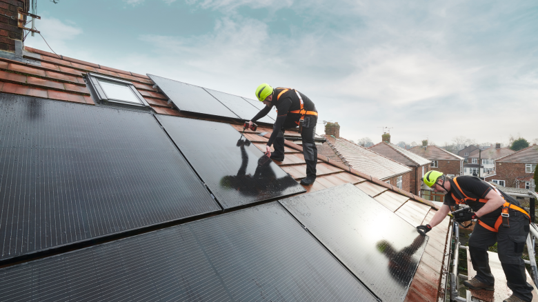 Two solar installers on a residential rooftop
