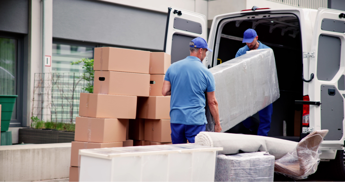 Workers in uniform unload furniture from a moving truck