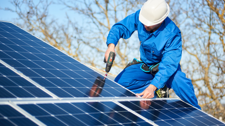 Professional installer mounting photovoltaic solar panels on a roof 