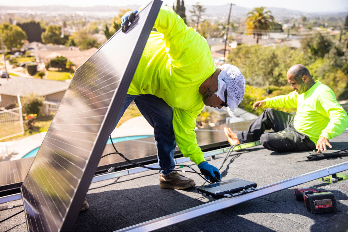 Workers attach solar panels to microinverters.