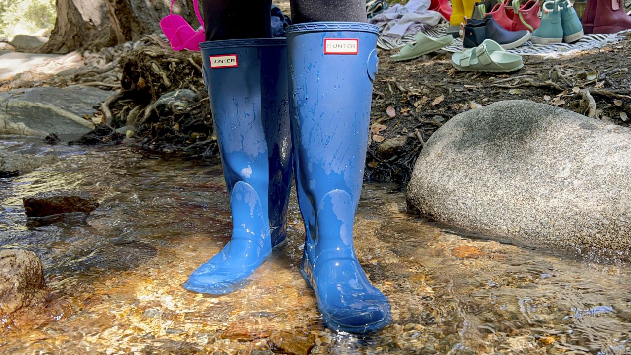 Person standing in river wearing tall rain boots