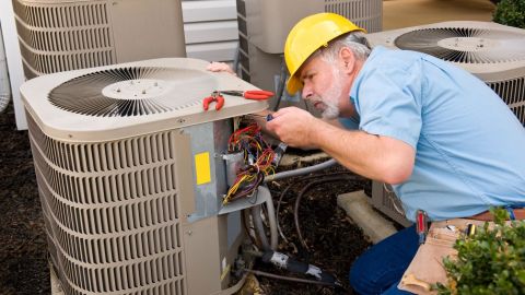 Technician inspects wiring in an HVAC unit.