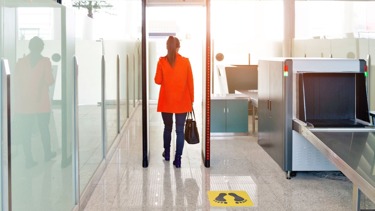 A photo of a person walking through a metal detector at an airport