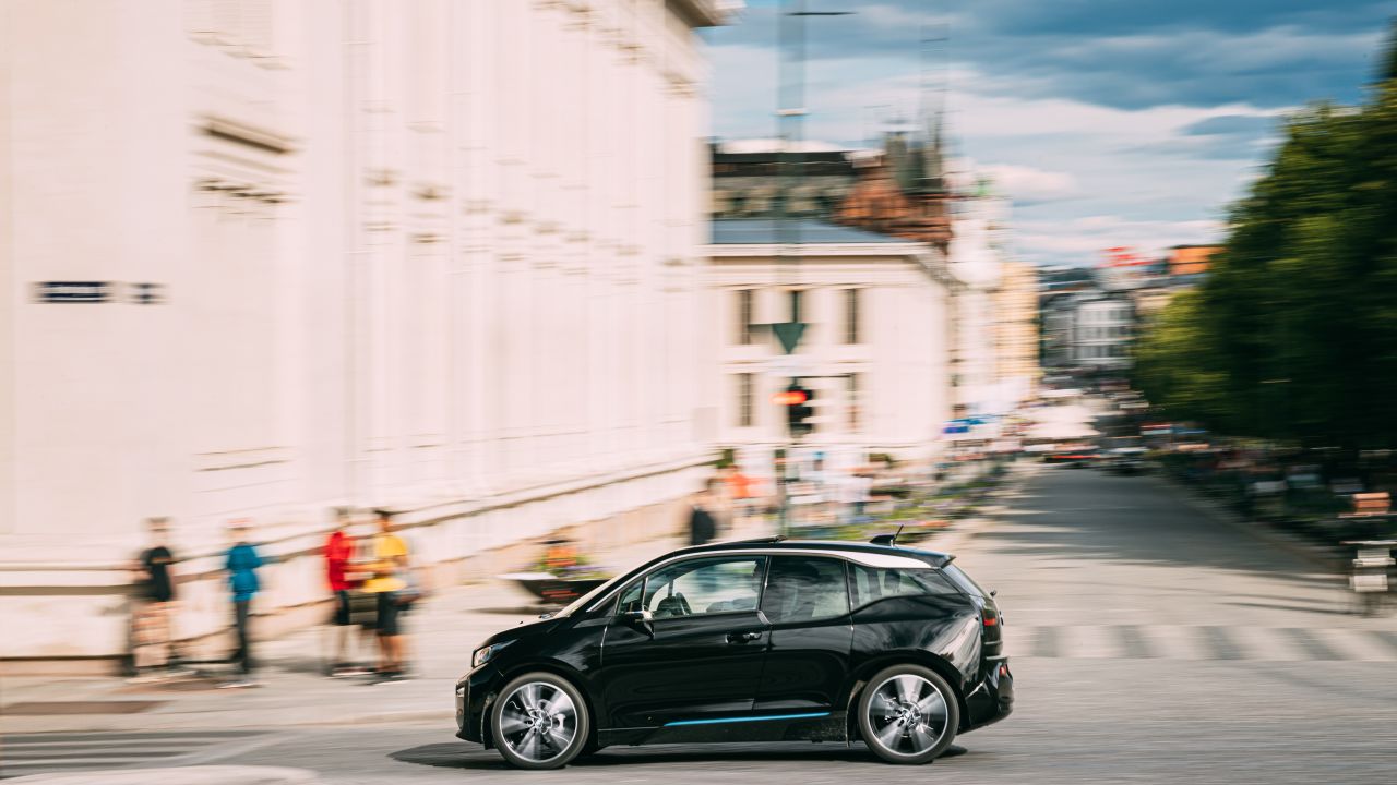 A black BMW i3 hatchback driving down a city street in Oslo, Norway.