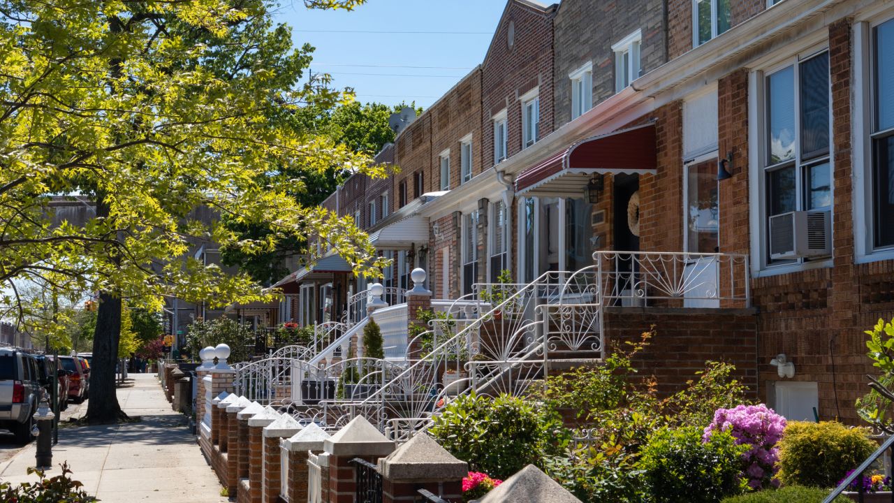 A row of brick homes along an empty sidewalk in Astoria, Queens, New York City.