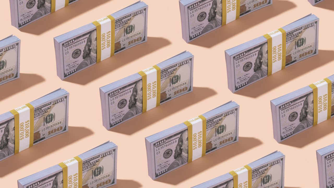 A pattern of $100 US dollar bills on an orange background.