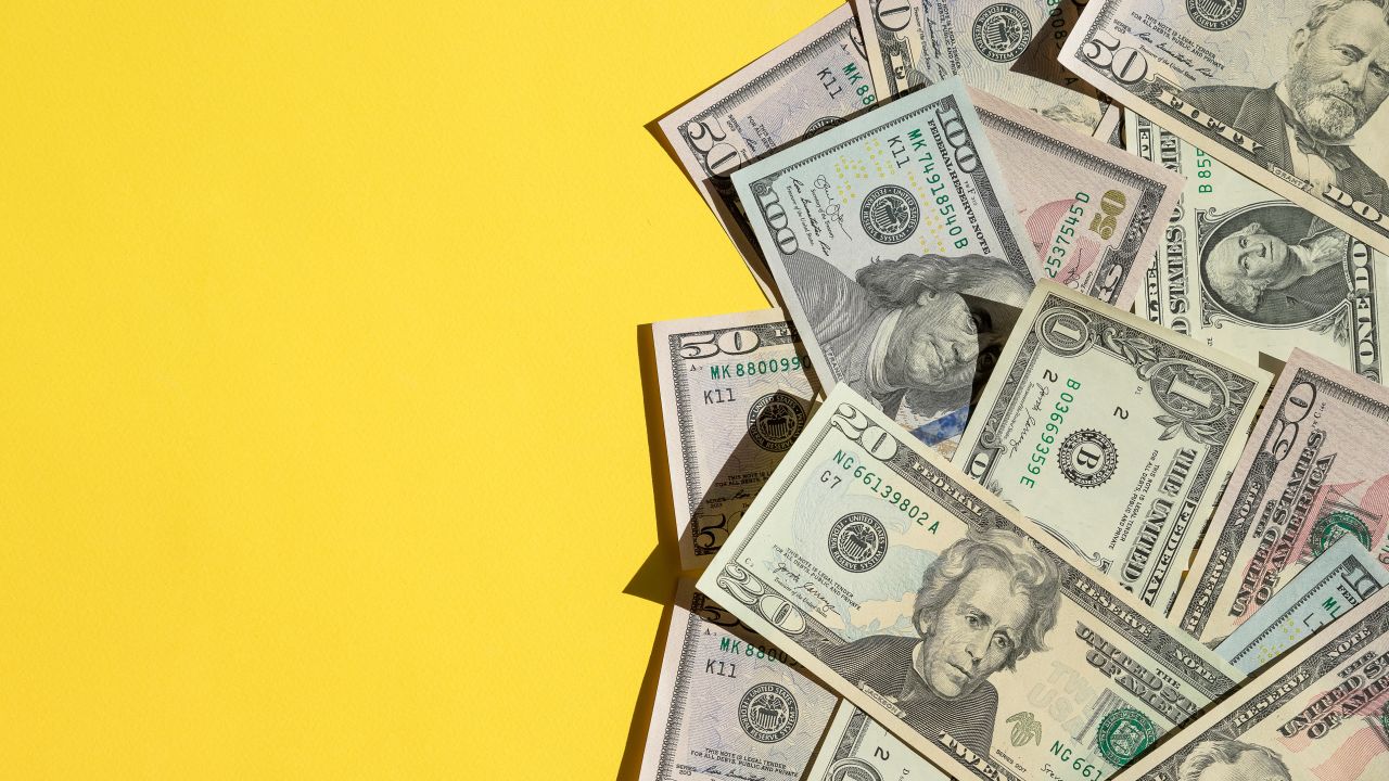 Various US dollar bills on a yellow background